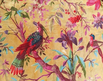 Puede incluir: Primer plano de una tela con un estampado floral y de pájaros. El diseño presenta pájaros coloridos posados en ramas con flores y follaje en tonos de rojo, morado, azul y verde sobre un fondo amarillo dorado.