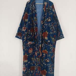 May include: A long, blue robe with a floral pattern in red, brown, and cream. The robe has a striped blue and white lining and two front pockets. It is hanging on a wooden hanger.