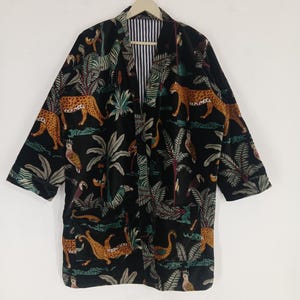 Könnte beinhalten: Schwarzer Kimono-Stil-Bademantel mit einem lebendigen Dschungel-Print mit Leoparden, Zebras und tropischem Laub. Der Bademantel hat ein gestreiftes Futter.