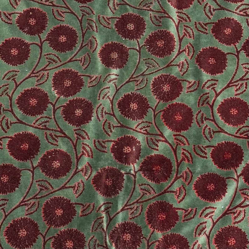 May include: A repeating pattern of burgundy flowers and vines on a muted green background. The floral design features large, round blooms with detailed centers and delicate leaves, creating a vintage aesthetic. The fabric has a soft, textured appearance.