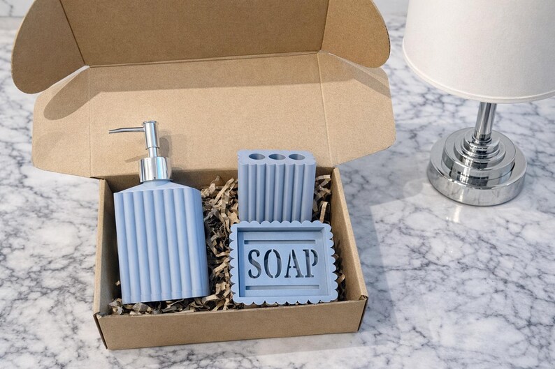 May include: A set of three ceramic mugs with a speckled, matte finish. The mugs are in shades of cream, light gray, and dark gray. Each mug has a simple, modern design and a rounded handle. The mugs are stacked on top of each other.