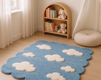Puede incluir: Una alfombra rectangular con borde festoneado, que presenta una base azul texturizada con varias formas de nubes blancas suaves y elevadas dispersas por la superficie. La alfombra tiene un aspecto afelpado y un diseño inspirado en nubes.