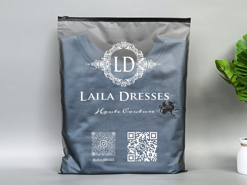 May include: A gray plastic bag with a black zipper, containing a blue shirt. The bag features the text "LAILA DRESSES Haute Couture" in white, along with a logo and QR codes for social media.