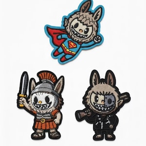 May include: Three embroidered patches with cartoon rabbit characters. One is dressed as Superman, another as a Roman soldier, and the third in a black jacket. Each patch has a unique design and colour scheme, suitable for clothing or accessories.