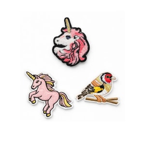 May include: Three embroidered patches on a white background. The patches include a pink unicorn head, a pink unicorn standing on its hind legs, and a colourful bird perched on a branch. The patches have a black border.