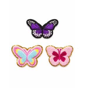 May include: Three butterfly-shaped embroidered patches. The top one is purple with white detailing and a black outline. The bottom left patch is light blue, yellow, and pink with a gold border. The bottom right is pink with a dark pink centre and a gold border.