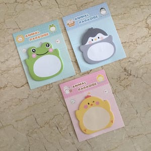 May include: Three animal-shaped sticky note pads. The pads feature a green frog, a grey penguin, and a yellow chick, each with a blank white space for notes. The pads are labelled "ANIMAL PARADISE".