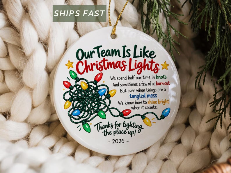 May include: A round white ceramic ornament featuring a graphic of tangled multi-coloured Christmas lights and the text: Our Team Is Like Christmas Lights, We spend half our time in knots, And sometimes a few of us burn out, But even when things are a tangled mess, We know how to shine bright when it counts, Thanks for lighting the place up!, - 2026 -.