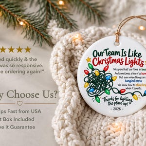 May include: A round white ceramic ornament featuring a graphic of tangled multi-coloured Christmas lights and the text: Our Team Is Like Christmas Lights, We spend half our time in knots, And sometimes a few of us burn out, But even when things are a tangled mess, We know how to shine bright when it counts, Thanks for lighting the place up, 2026.
