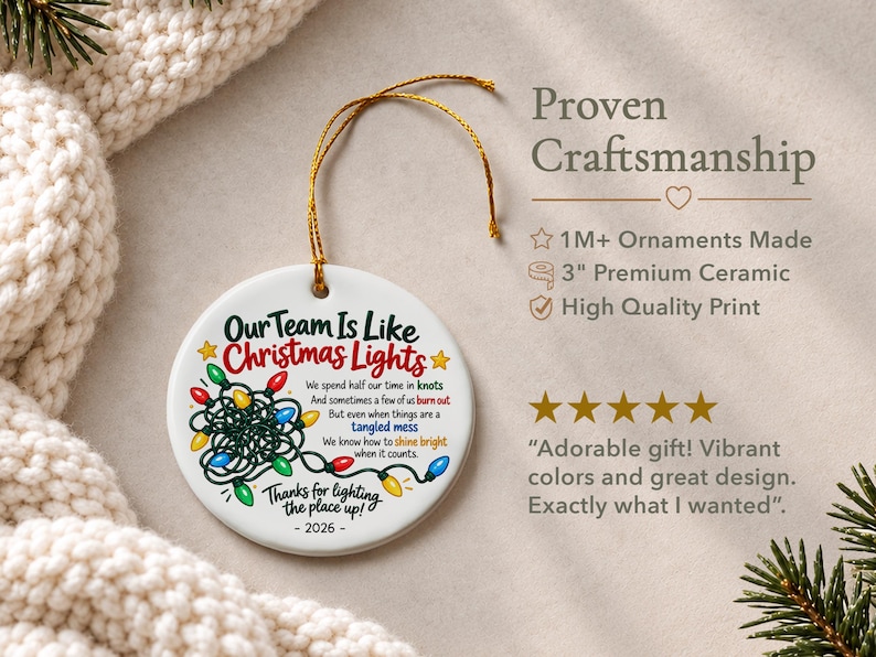 May include: A round white ceramic ornament with a gold hanging string. The design features a graphic of tangled multi-coloured Christmas lights and text that reads: Our Team Is Like Christmas Lights, 2026, and other phrases. It measures 7.62 cm.