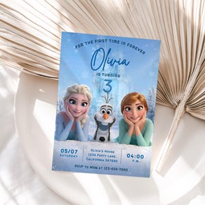 May include: A rectangular birthday invitation card featuring a light blue background with snowflakes and a castle. It displays the text FOR THE FIRST TIME IN FOREVER, Olivia IS TURNING 3, with images of two animated characters and a snowman. Includes date, time, address, and RSVP details.