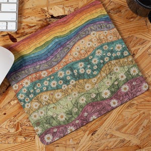 May include: A colorful mousepad with a rainbow design and daisy flower pattern. The mousepad is rectangular and features a white mouse and a keyboard in the background. The design includes shades of orange, yellow, green, blue, and purple.