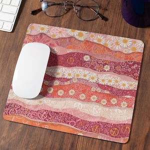 Può includere: Un tappetino per mouse decorativo con un design colorato e ondulato. Il motivo include strati di rosa, arancione e bordeaux con motivi a margherita e simboli di pace. Un mouse per computer bianco è appoggiato sul tappetino.