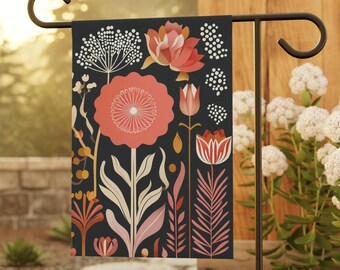May include: A garden flag with a black background and a colorful floral pattern. The flowers are pink, red, and white. The flag is attached to a black metal stand.