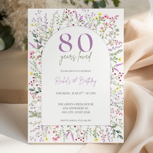 Può includere: Un invito a tema floreale per un ottantesimo compleanno. Il design presenta un arco con il testo "80 years loved" in viola, circondato da fiori colorati. Il testo aggiuntivo include i dettagli del compleanno e le informazioni RSVP.