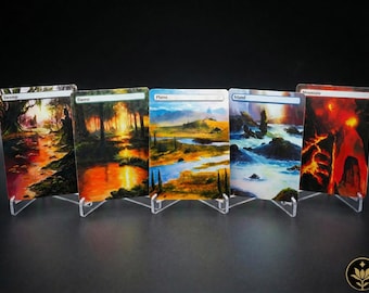 Könnte beinhalten: Fünf Landschaftskunstkarten, jeweils in einem transparenten Acrylständer ausgestellt. Die Karten zeigen Szenen eines Sumpfes, Waldes, einer Ebene, einer Insel und eines Berges. Die Kunstwerke weisen lebendige Farben und detaillierte Bilder auf, mit Textbeschriftungen oben auf jeder Karte.