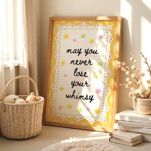 以下が含まれることがあります： 白い背景に黒い文字で「may you never lose your whimsy」と書かれた長方形の額入りウォールアート。周囲はピンクとライムグリーンの小さな星の形とスカラップ状の縁取りで飾られた黄色い枠で囲まれています。