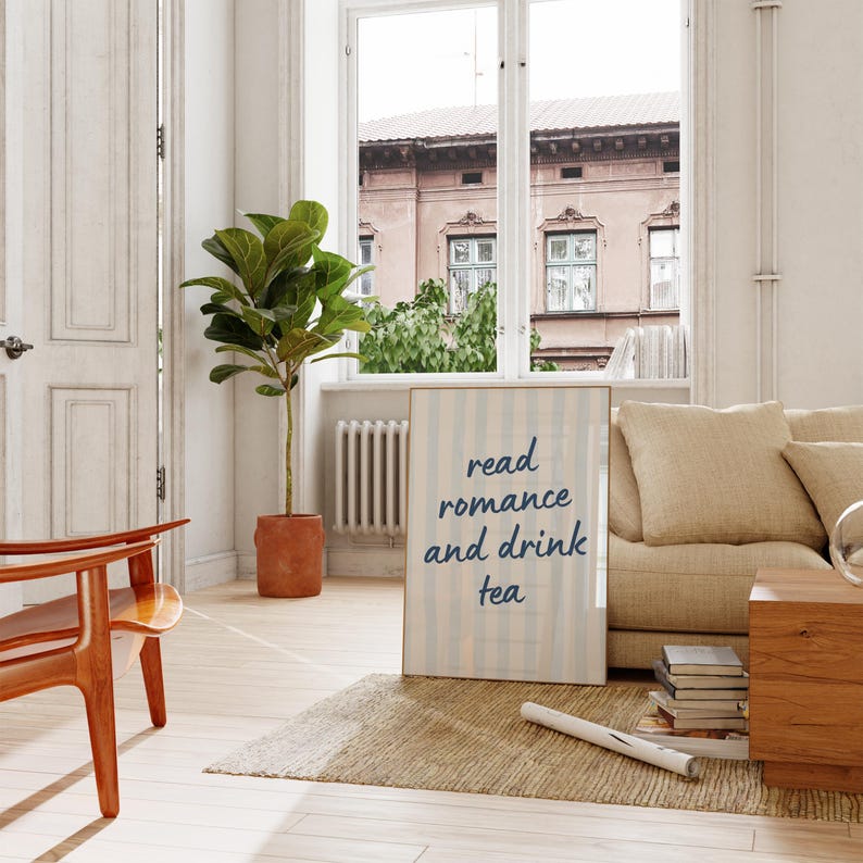 May include: A rectangular framed wall art piece featuring a light blue and white vertical striped background with the dark blue text read romance and drink tea centered on the surface. The print is displayed in a simple wooden frame.