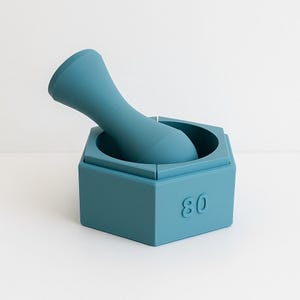 May include: A teal mortar and pestle set. The hexagonal mortar has the number "80" on the side. The curved pestle fits inside. The set is made of a solid material. The measurements are in centimetres.