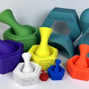 May include: A collection of colorful, 3D-printed mortar and pestle sets in various sizes and colors, including purple, green, yellow, white, blue, and orange. The bases are hexagonal and numbered. Additional geometric shapes are in the background.