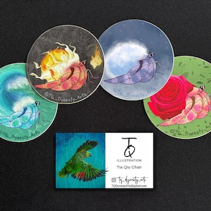 May include: A collection of round stickers featuring illustrated hermit crabs with various backgrounds: a wave, fire, a moon, a rose. A business card with a green parrot illustration and artist information is also included.