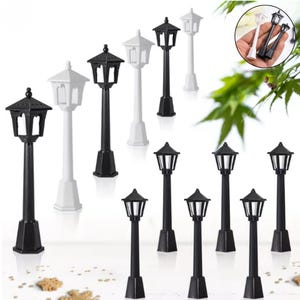 May include: Collection of miniature black and white street lamps. The lamps have a classic design with a hexagonal top and a rectangular base. Some lamps are tall, while others are shorter.