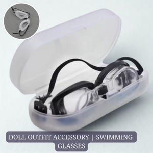 May include: Clear swimming goggles with black straps inside a translucent white case. A smaller inset image shows a pair of goggles. Text at the bottom reads: DOLL OUTFIT ACCESSORY | SWIMMING GLASSES.