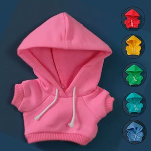 May include: A pink miniature hoodie with a drawstring hood and short sleeves. The image also shows examples of red, yellow, green, teal, and blue hoodies. The hoodies are likely designed for a doll or small toy.