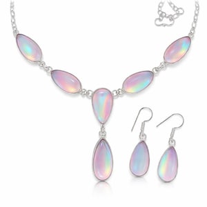 Può includere: Un set di gioielli color argento con collana e orecchini abbinati. La collana presenta una serie di pietre iridescenti ovali e a goccia. Gli orecchini sono a goccia, con una pietra iridescente abbinata.