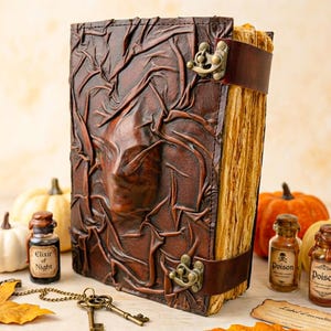May include: A brown leather-bound book with a textured cover and a clasp closure. The book has a leather strap and aged pages. Decorative elements include small potion bottles, keys, and pumpkins, creating a Halloween theme.