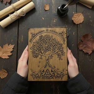 May include: A wooden journal with a carved tree design, held by hands. The journal is surrounded by parchment scrolls, autumn leaves, an inkwell, and a quill on a dark wooden surface. The tree design includes Celtic knotwork.