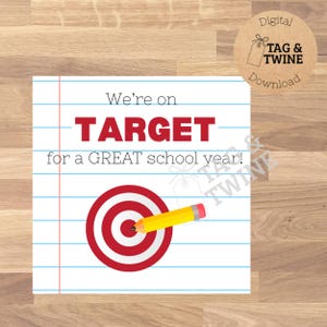 May include: A square digital graphic on a white lined paper background featuring the red text "We're on TARGET for a GREAT school year!" with a red and white bullseye target and a yellow pencil with a pink eraser pointing toward the center.