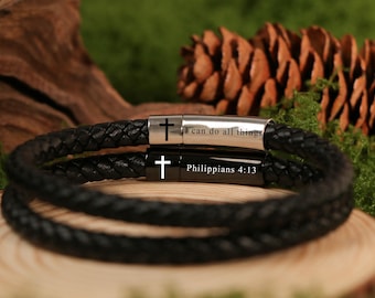 May include: Two black braided leather bracelets with silver and black clasps. The silver clasp has a cross and the text "I can do all things." The black clasp has a cross and the text "Philippians 4:13."