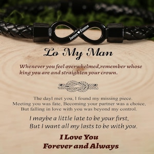 May include: Black braided leather bracelet with an infinity symbol clasp. The clasp is engraved with the names "James" and "Emma". The text "Lo My Man" and a romantic message are printed below the bracelet.