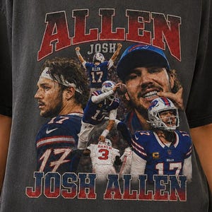 May include: A charcoal gray short-sleeve t-shirt featuring a vintage-style graphic print of football player Josh Allen. The design includes multiple action shots of the athlete in a blue and red uniform, with the text ALLEN and JOSH ALLEN.
