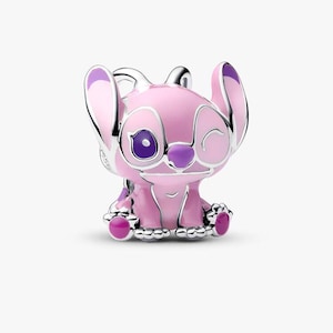 Puede incluir: Un charm de plata con forma de personaje que gui&ntilde;a un ojo con orejas grandes, con detalles de esmalte rosa claro en el cuerpo y las orejas, un ojo morado oscuro y una nariz morada. El personaje est&aacute; en posici&oacute;n sentada con almohadillas visibles.