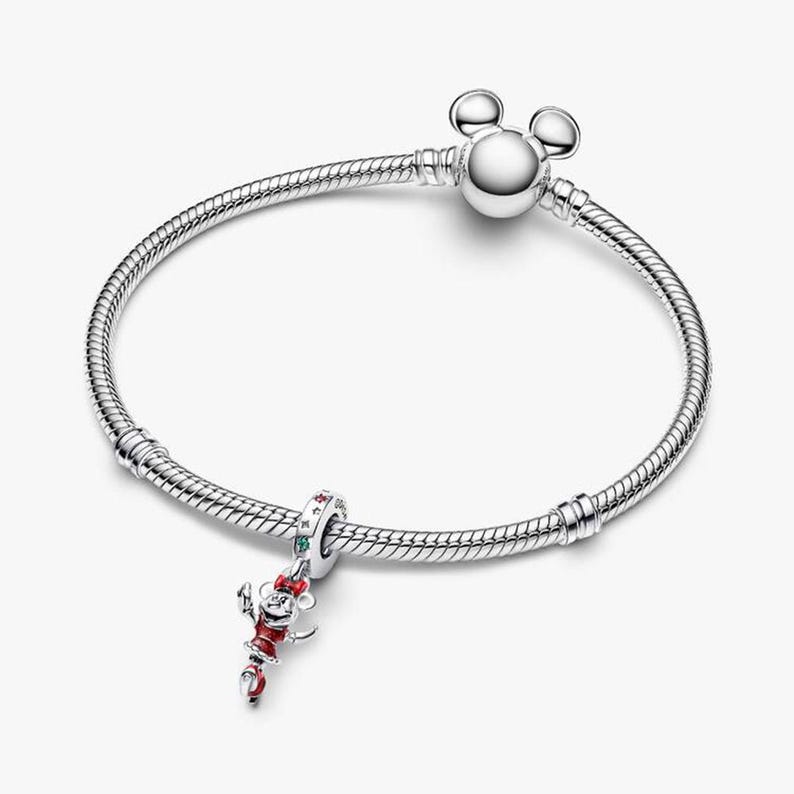 May include: A silver bracelet with a Mickey Mouse charm. The charm is red, white, and black with green accents. The bracelet has a round clasp with Mickey Mouse ears.