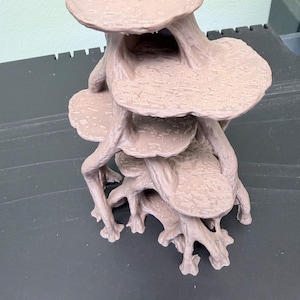 May include: A light brown, multi-tiered, three-dimensional structure featuring several flat, circular platforms connected by branching, root-like supports. The surface of each platform has a textured, uneven finish, and the entire object is molded as a single piece.