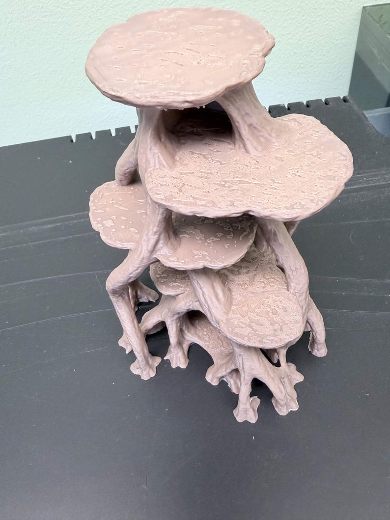 May include: A light brown, multi-tiered, three-dimensional structure featuring several flat, circular platforms connected by branching, root-like supports. The surface of each platform has a textured, uneven finish, and the entire object is molded as a single piece.