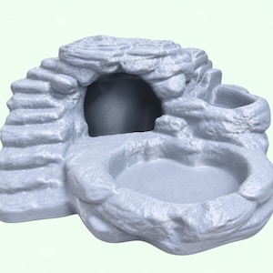 May include: A light grey, textured rock-shaped hideout for small animals, featuring a hollow cave entrance on the left side, a set of moulded steps leading to the top, and a shallow, circular basin area positioned at the front for resting or feeding.