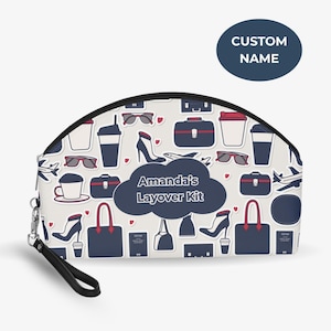 Könnte beinhalten: Eine weiße Kosmetiktasche mit schwarzem Reißverschluss und Handschlaufe. Die Tasche ist mit Illustrationen zum Thema Reisen versehen, darunter Sonnenbrillen, Kaffeetassen und Handtaschen. Der Text "Amanda's Layover Kit" ist auf der Tasche zu sehen.