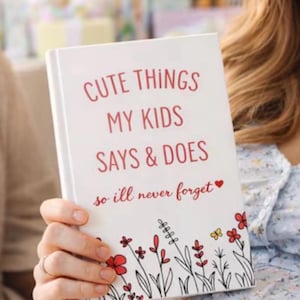 May include: A white hardcover journal with the red text CUTE THINGS MY KIDS SAYS & DOES so ill never forget and a small red heart. The bottom of the cover features a black and red line art illustration of various wildflowers and a small yellow butterfly.
