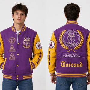 Könnte beinhalten: Eine violette und goldene Collegejacke mit den griechischen Buchstaben Phi Alpha Delta auf der Vorderseite, dem Wappen der Verbindung sowie dem Schriftzug International Foundation und Tureaud auf der Rückseite und den Jahreszahlen 1972 und 1902.