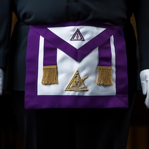 Può includere: Un grembiule massonico bianco e viola con frange dorate e simboli ricamati. Il grembiule è indossato sopra un abito nero con guanti bianchi. Presenta un triangolo e altre forme geometriche.