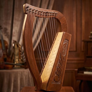 Pode incluir: Uma harpa de madeira com um acabamento castanho quente, com uma estrutura curva e inúmeras cordas. A caixa de ressonância tem um painel de madeira mais claro com desenhos florais esculpidos. A harpa é exibida em um suporte de madeira, com um fundo desfocado.