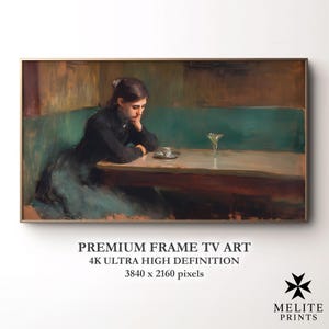 Op de afbeelding: Een ingelijste print van een schilderij dat een vrouw in een café aan een tafel toont. Ze draagt een donkere jurk en rust haar hoofd op haar hand. Een kopje en een glas staan op tafel. De tekst "PREMIUM FRAME TV ART" en "4K ULTRA HIGH DEFINITION" is zichtbaar.