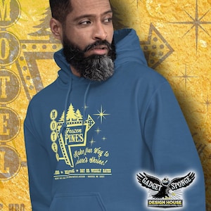 Może przedstawiać: Niebieska bluza z kapturem z grafiką vintage'owego znaku motelu z tekstem "Frozen Pines" i sloganem "Make your way to Dave's Shrine!" Znak jest ż&oacute;łty z białymi gwiazdami i białą obw&oacute;dką. Tekst na bluzie jest ż&oacute;łty.