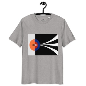 May include: A grey t-shirt with a graphic design. The design features a half-circle in orange and white, a blue circle, and a black rectangle with white lines extending from it. The shirt is hanging on a black hanger.