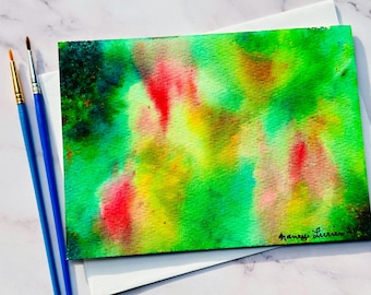 Tarjeta de acuarela original con colores navideños: Hoja de arce abstracta y colorida, pintada a mano.