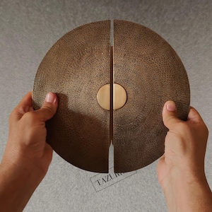 Può includere: Maniglie per porte semicerchiate color bronzo con superficie strutturata. Le maniglie sono divise in due metà, con un accento circolare color ottone al centro. Le maniglie sono tenute da mani su uno sfondo neutro.